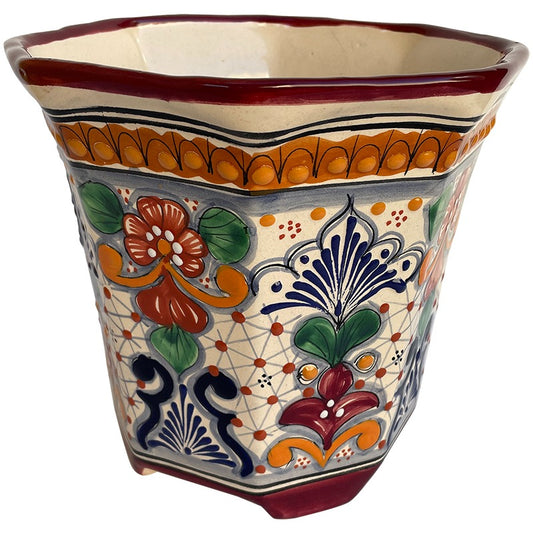 A handmade ceramic planter with a hand-painted Talavera-style design featuring orange, green, blue, and red floral motifs on a cream background.