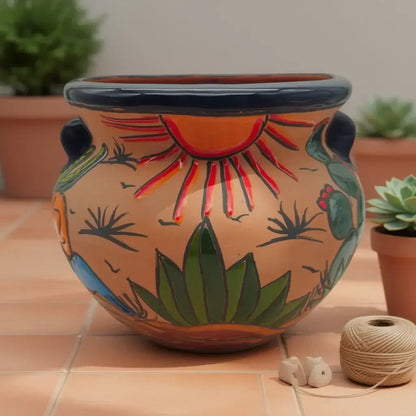 Decorative pot with sun and cactus design on a tiled floor