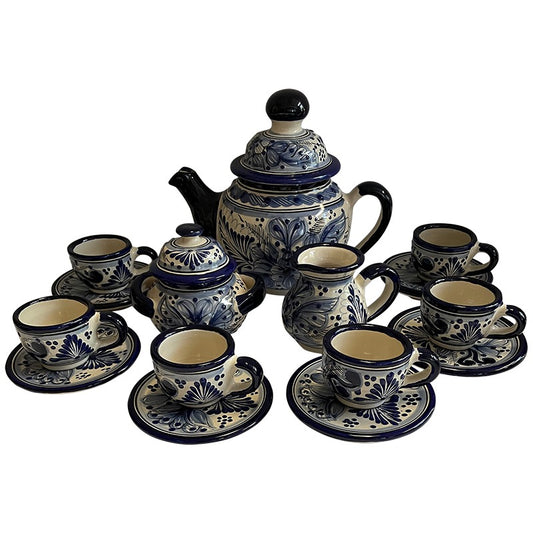 A ceramic coffee or tea set with a teapot, sugar bowl, creamer, and multiple cups with saucers, all decorated in a blue and cream floral pattern on a white background.